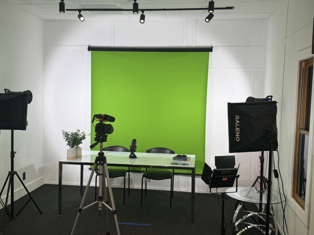 A media production room with a camera, lights, and a green screen.