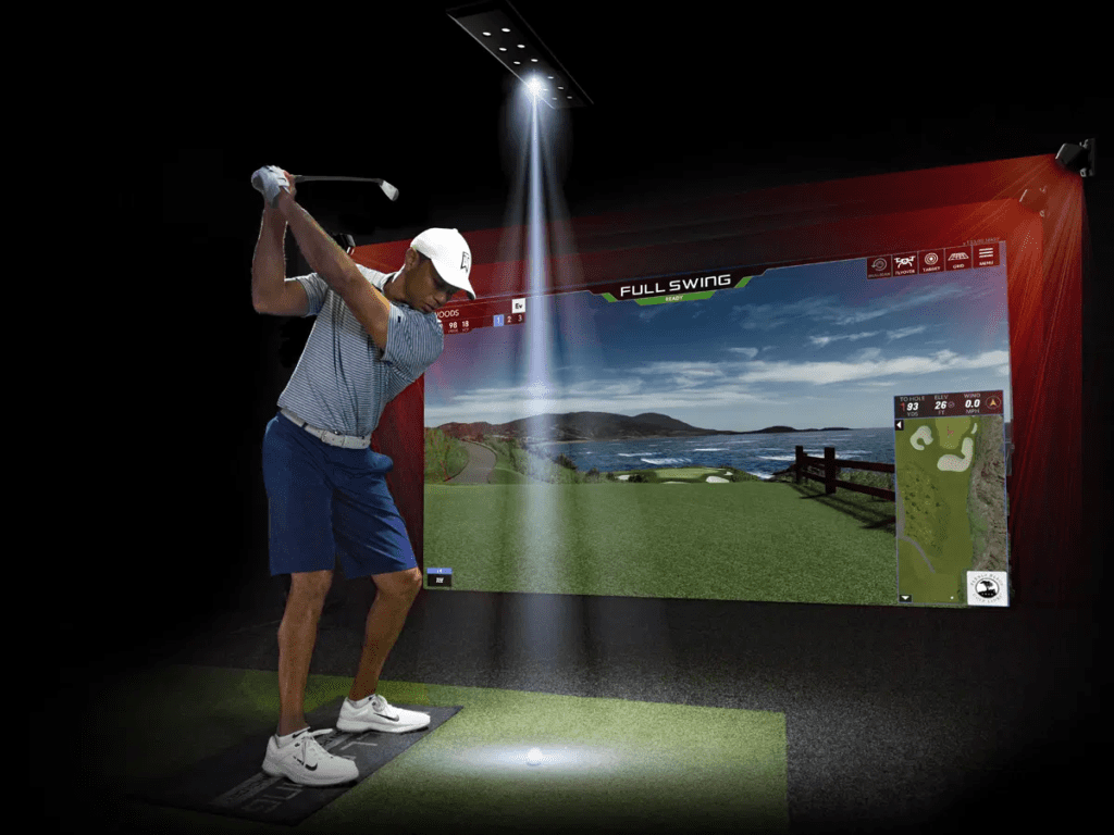 A man with a golf club in front of a screen playing the video game Golf Simulator.
